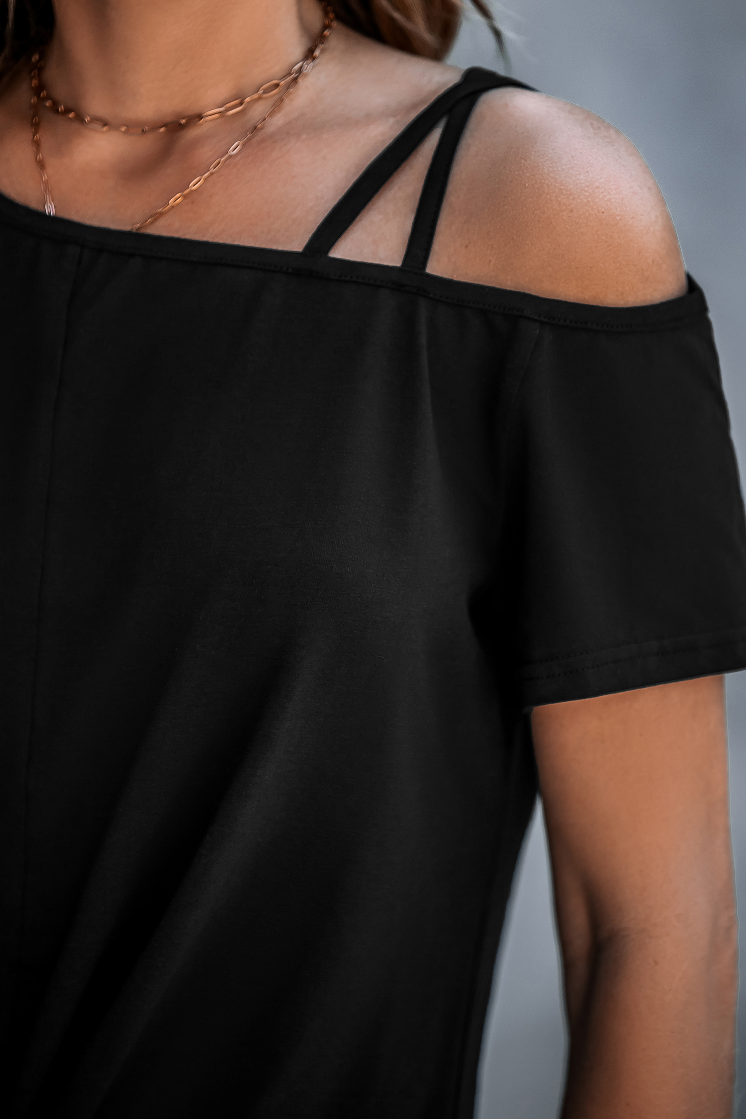 Camiseta negra con corte asimétrico y hombros retorcidos